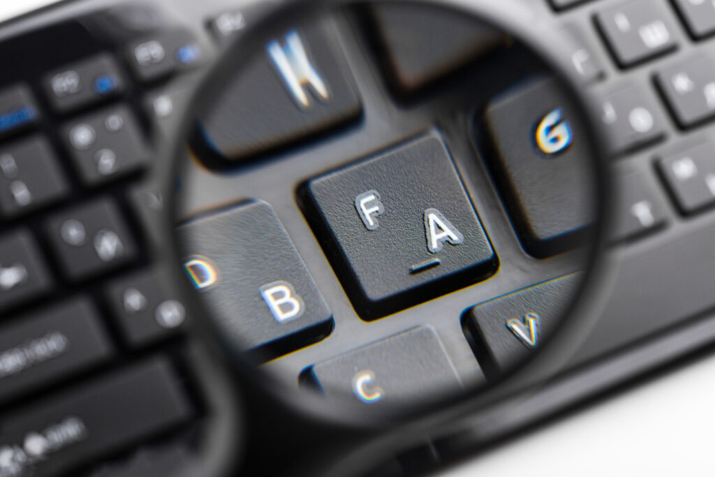 Lupa powiększająca klawisze "F" i "A" na klawiaturze komputerowej z rozmazanym tłem innych klawiszy.