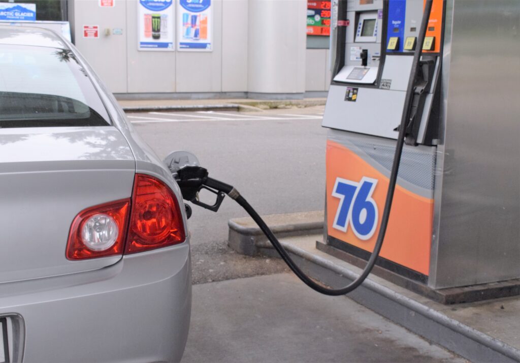 Samochód tankujący benzynę przy dystrybutorze paliwa na stacji benzynowej, reprezentujący wprowadzenie nowej benzyny E10