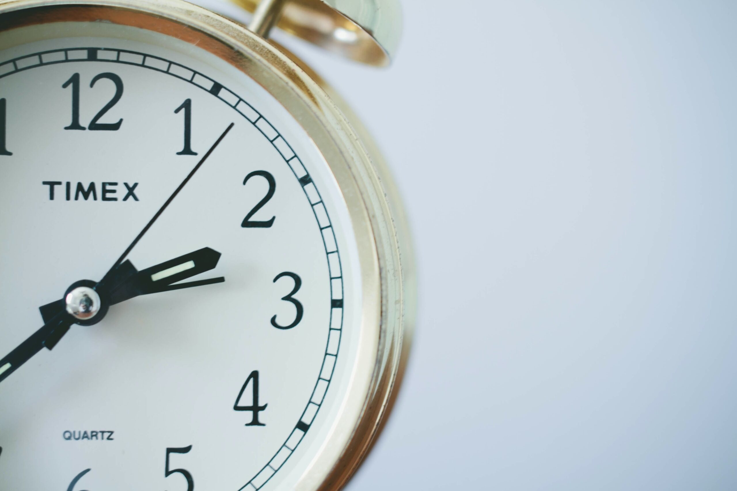 Zbliżenie na klasyczny biały zegar marki Timex wskazujący godzinę pierwszą, symbolizujący wartość i znaczenie dobrze zarządzanego czasu
